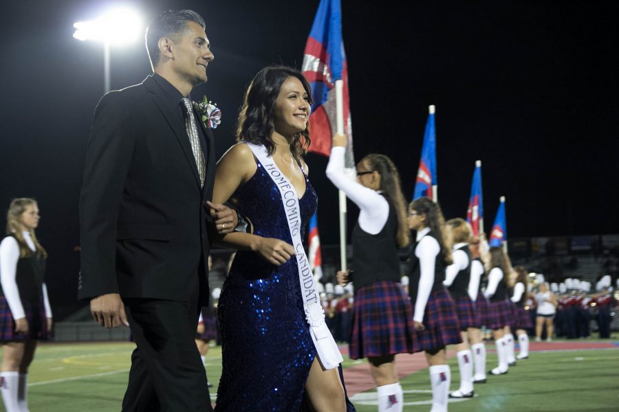 2017 Homecoming Queen Belle Enriquez walks down the football field with her father.